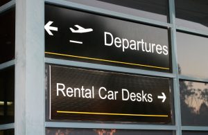 Airport departure and rental car direction sign. Rental car accidents, insurance coverage and defect recalls questions.