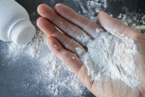Woman who hand is extended and she is putting talcum powder in the hand.